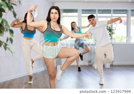 Expressive Hispanic teenage girl dancing hip-hop with group in studio 123917999