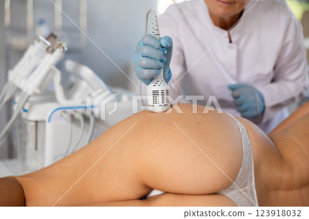 Hardware anti-cellulite procedure on butt of young woman in beauty clinic Hardware anti-cellulite procedure on butt of young woman in beauty clinic 123918032