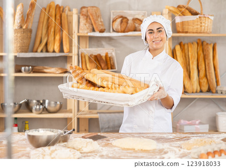 Young female baker with basket of baguettes Young female baker with basket of baguettes 123918033