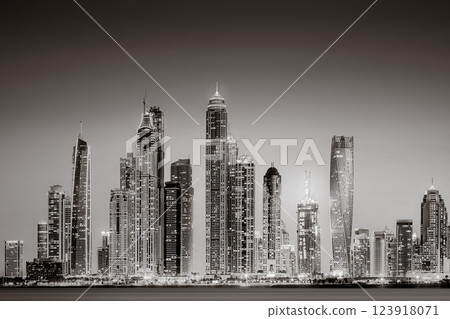 Urban city skyline with illuminated skyscrapers and waterfront railing in black and white at night, Dubai Marina bay UAE Urban city skyline with illuminated skyscrapers and waterfront railing in black and white at night, Dubai Marina bay UAE 123918071