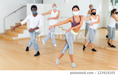 People in protective masks learning swing steps at dance class 123918105