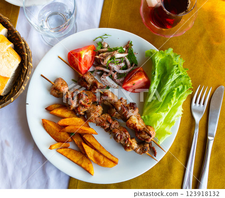 Lamb shish kebab with lettuce, tomatoes and French fries closeup. Turkish cuisine Lamb shish kebab with lettuce, tomatoes and French fries closeup. Turkish cuisine 123918132