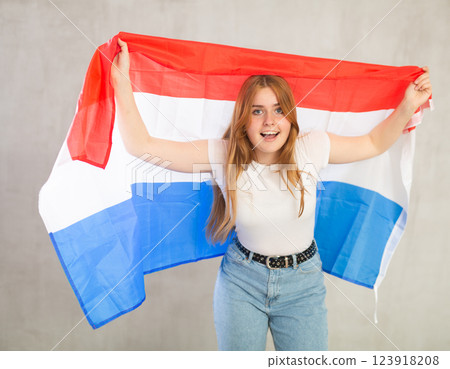 smiling girl in arms raised above head holds canvas of national flag of Netherlands smiling girl in arms raised above head holds canvas of national flag of Netherlands 123918208