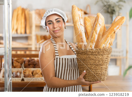 Young female seller with baguettes in basket Young female seller with baguettes in basket 123918219