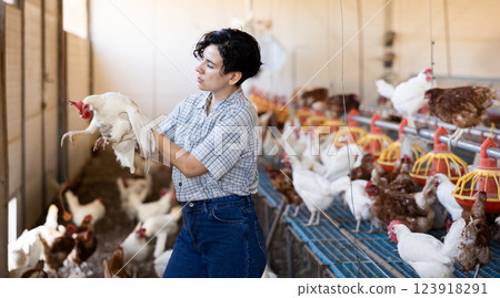 Smiling latin woman in plaid shirt working in chicken farm Smiling latin woman in plaid shirt working in chicken farm 123918291