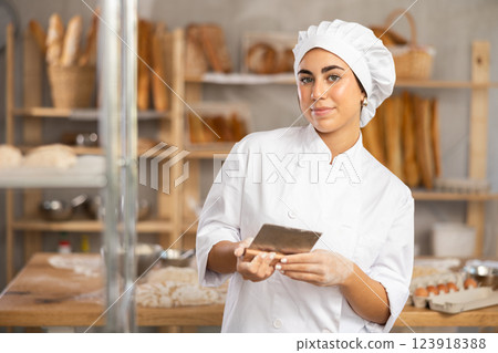 Young female baker with dough scraper 123918388