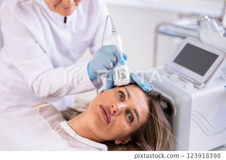 Young woman experiencing facial cryotherapy procedure using ice hammer Young woman experiencing facial cryotherapy procedure using ice hammer 123918398