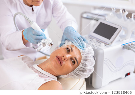 Young woman undergoing facial skin therapy using airbrush wuth atomized nutrients Young woman undergoing facial skin therapy using airbrush wuth atomized nutrients 123918406