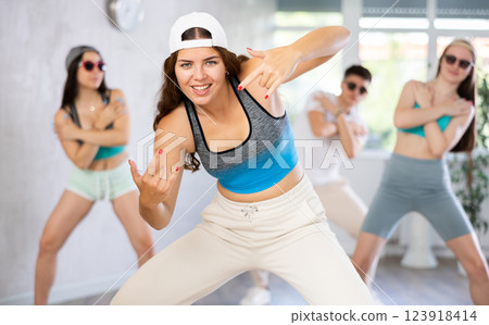 Female teen teacher with young girls in dark glasses and ball cap dance Jazz-modern at lesson Female teen teacher with young girls in dark glasses and ball cap dance Jazz-modern at lesson 123918414
