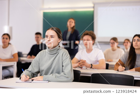 Group of school teenagers with pens and notebooks studying in classroom 123918424
