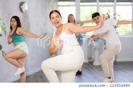 Girl teen perform choreographic exercise and teach energetic waacking dance with friends Girl teen perform choreographic exercise and teach energetic waacking dance with friends 123918494