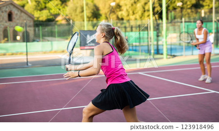 Sportive caucasian girl in pink t-shirt and skirt with racquet playing tennis 123918496