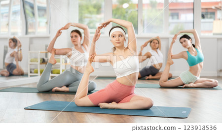 Young girls practicing pigeon pose in pilates studio Young girls practicing pigeon pose in pilates studio 123918536