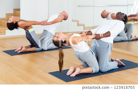 Women and men performing paired yoga exercises during group training 123918703