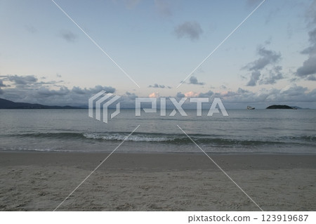 Serene beach view with gentle waves and clouds at sunset Serene beach view with gentle waves and clouds at sunset 123919687