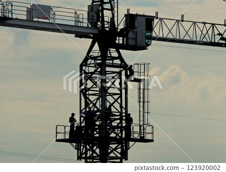 Silhouettes Of Workers On A Tower Crane At Works Silhouettes Of Workers On A Tower Crane At Works 123920002