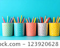 Colorful polka-dotted pen holders filled with writing supplies on a bright blue background, arranged neatly 123920628