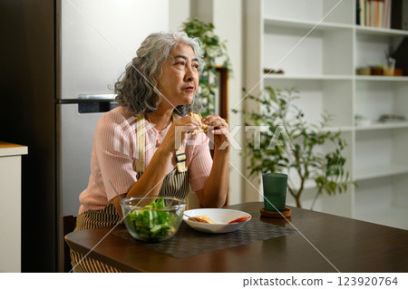 Mature woman enjoying a healthy breakfast at a wooden dining table 123920764