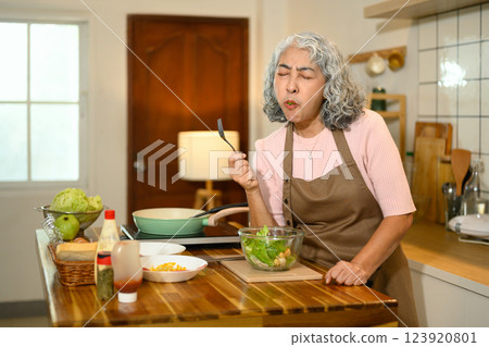 Senior woman with gray hair enjoying a healthy salad in the kitchen Senior woman with gray hair enjoying a healthy salad in the kitchen 123920801