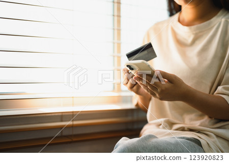 Close up of woman making an online purchase using a credit card and mobile phone. Close up of woman making an online purchase using a credit card and mobile phone. 123920823