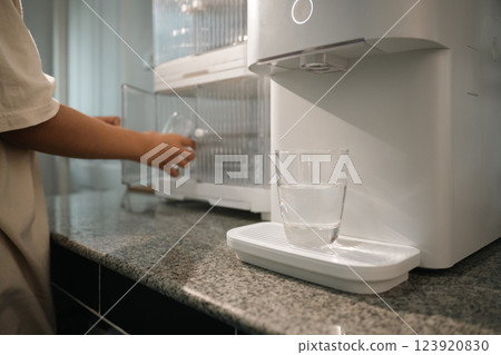 A transparent glass filled with filtered water from a high tech water purifier on kitchen counter 123920830