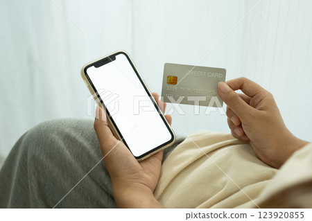 Hand holding smartphone with blank screen and credit card. Digital payments and financial security concept 123920855