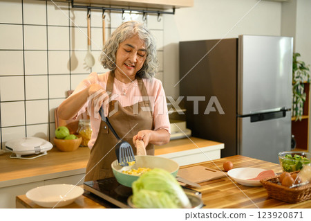 Happy senior woman preparing a healthy meal in a warm kitchen Happy senior woman preparing a healthy meal in a warm kitchen 123920871