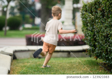 Young Boy Running and Playing Outdoors in the Park in defocus Young Boy Running and Playing Outdoors in the Park in defocus 123921083
