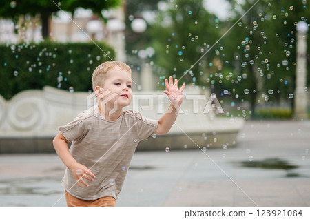 Happy Child Playing with Soap Bubbles Outdoors 123921084