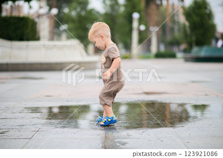 Toddler Playing in a Rain Puddle Outdoors 123921086