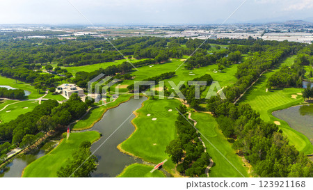 Panoramic aerial view of a golf course with ponds, sand bunkers, and a clubhouse surrounded by nature 123921168