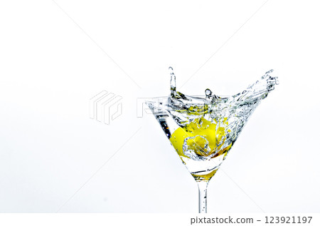 Close-up of water drop falling into a glass on white background Close-up of water drop falling into a glass on white background 123921197