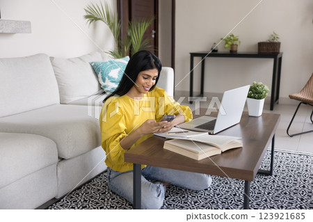 Woman distracted from studying process using smartphone Woman distracted from studying process using smartphone 123921685