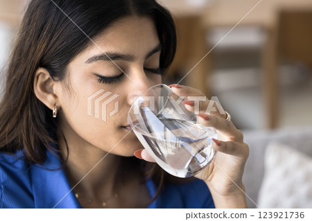 Closeup face view of young woman drinking glass of water Closeup face view of young woman drinking glass of water 123921736