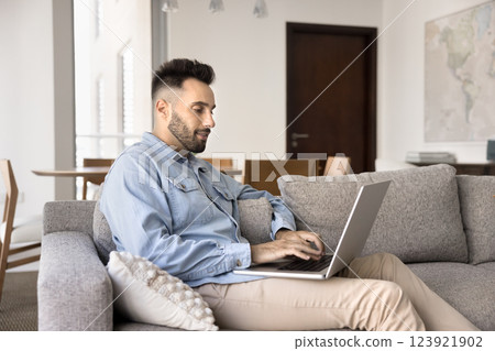 Handsome Spaniard man resting at home using his modern laptop 123921902