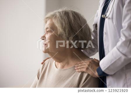 Doctor stand behind senior woman holding hands on patient shoulders 123921920