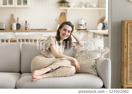 Happy gen z woman rest on sofa at home kitchen 123922002