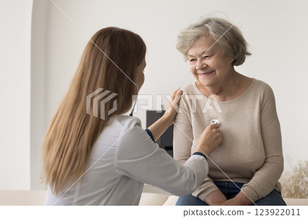 Confident female doctor apply stethoscope to mature woman patient chest 123922011