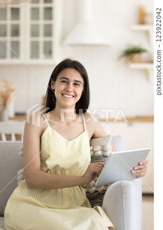 Portrait pretty smiling teen girl sitting on sofa holding tablet Portrait pretty smiling teen girl sitting on sofa holding tablet 123922042