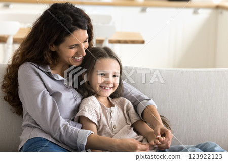 Happy young mother hug little daughter sitting on cozy sofa 123922123