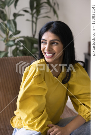 Woman sit in chair, looking into distance with joyful expression 123922145
