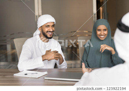 Arabian colleague engaged in enthusiastic conversation seated at conference table 123922194