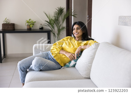 Woman looking away with contented smile while relaxing on couch 123922203