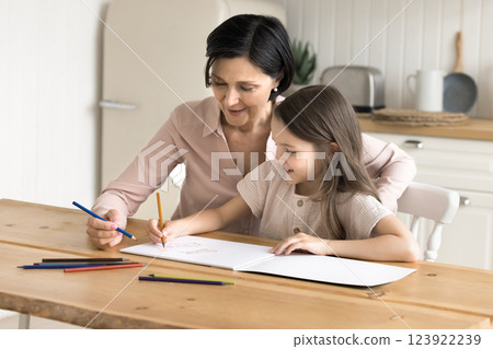 Smiling mature grandma help little granddaughter draw sketches in album Smiling mature grandma help little granddaughter draw sketches in album 123922239