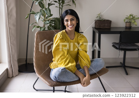 Beautiful Indian woman sitting in woven chair in relaxed pose Beautiful Indian woman sitting in woven chair in relaxed pose 123922312