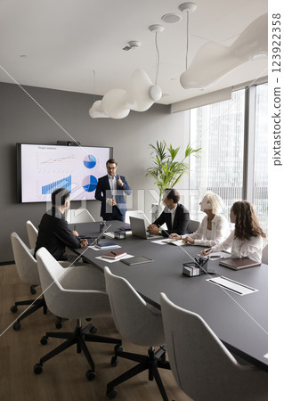 Businesspeople group gather by conference table listen to coach speaking 123922358