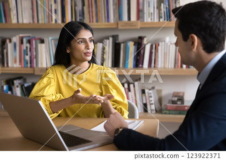 Confident millennial female tutor consult young male student at library 123922371