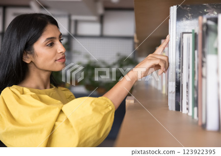 Young girl book store client select paper volumes on shelf Young girl book store client select paper volumes on shelf 123922395
