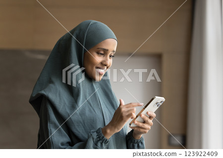 Woman in traditional abaya using smartphone at workplace Woman in traditional abaya using smartphone at workplace 123922409