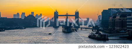 As the sun sets over London, the iconic Tower Bridge and HMS Belfast create a stunning silhouette against a vibrant sky, highlighting the city's rich maritime history and landscape. As the sun sets over London, the iconic Tower Bridge and HMS Belfast create a stunning silhouette against a vibrant sky, highlighting the city's rich maritime history and landscape. 123922423